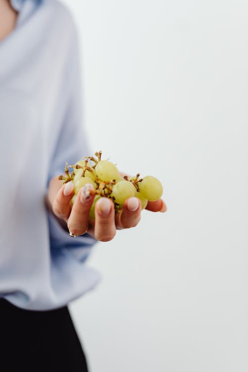 Close Up Photo of a Person Holding Grapes