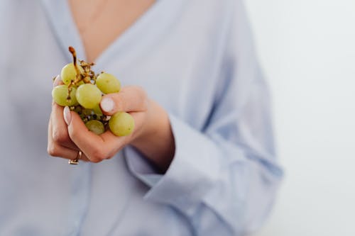 Close-Up Shot of a Person Holding Green Grapes