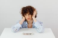 Woman in Blue Long Sleeve Blouse Near the Money on Table