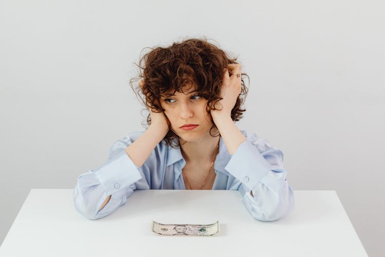 Woman In Blue Long Sleeve Blouse Near The Money On Table