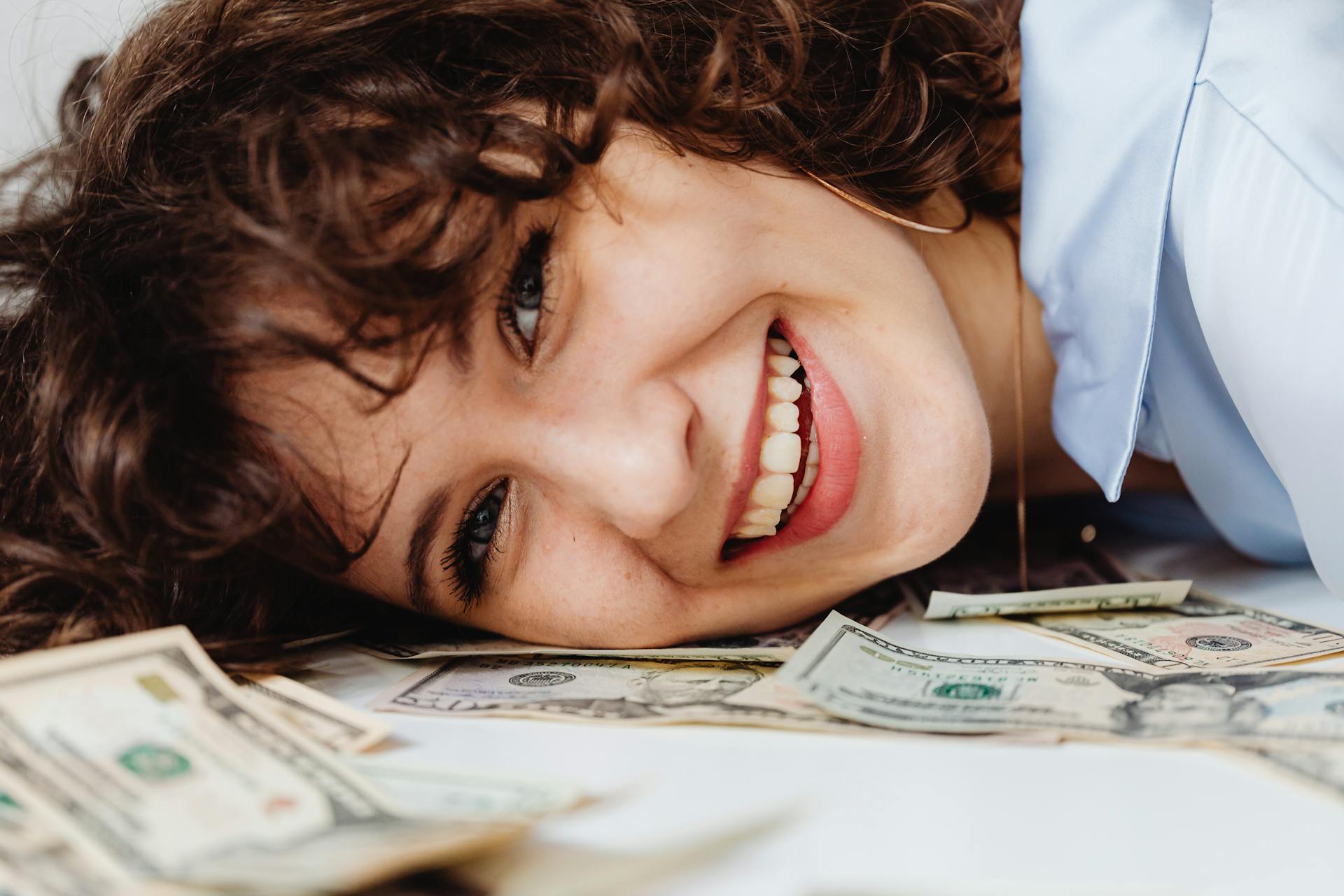 A Happy Woman Resting Her Head on a Table with Paper Money