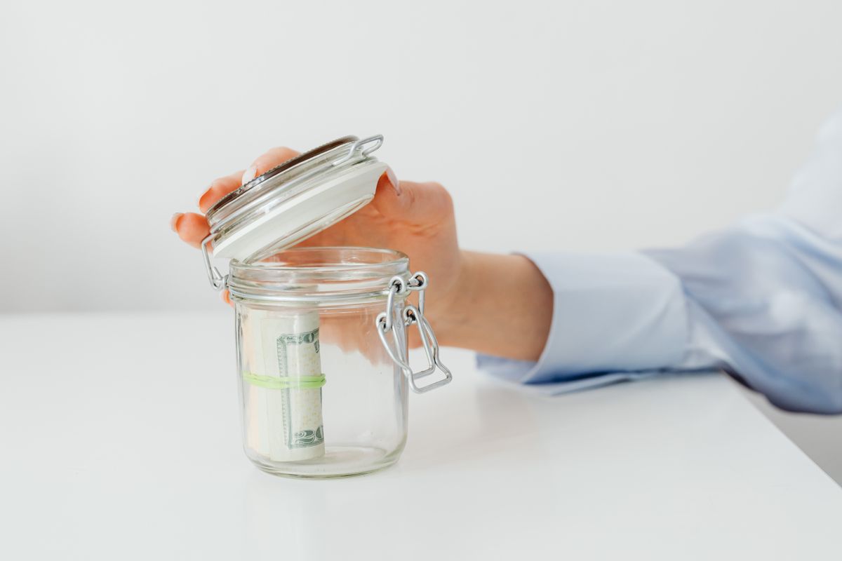 Persona guardando monedas en un frasco de ahorro para juntar el dinero del regreso a clases durante todo el año