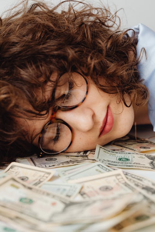 Close-Up Shot of a Woman Sleeping on Paper Money
