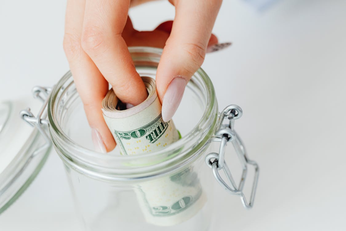 Free Close-Up Shot of a Person Saving Money in the Glass Jar Stock Photo