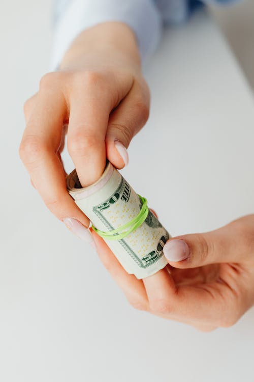 Free Close-Up Shot of a Person Holding Rolled Paper Money Stock Photo