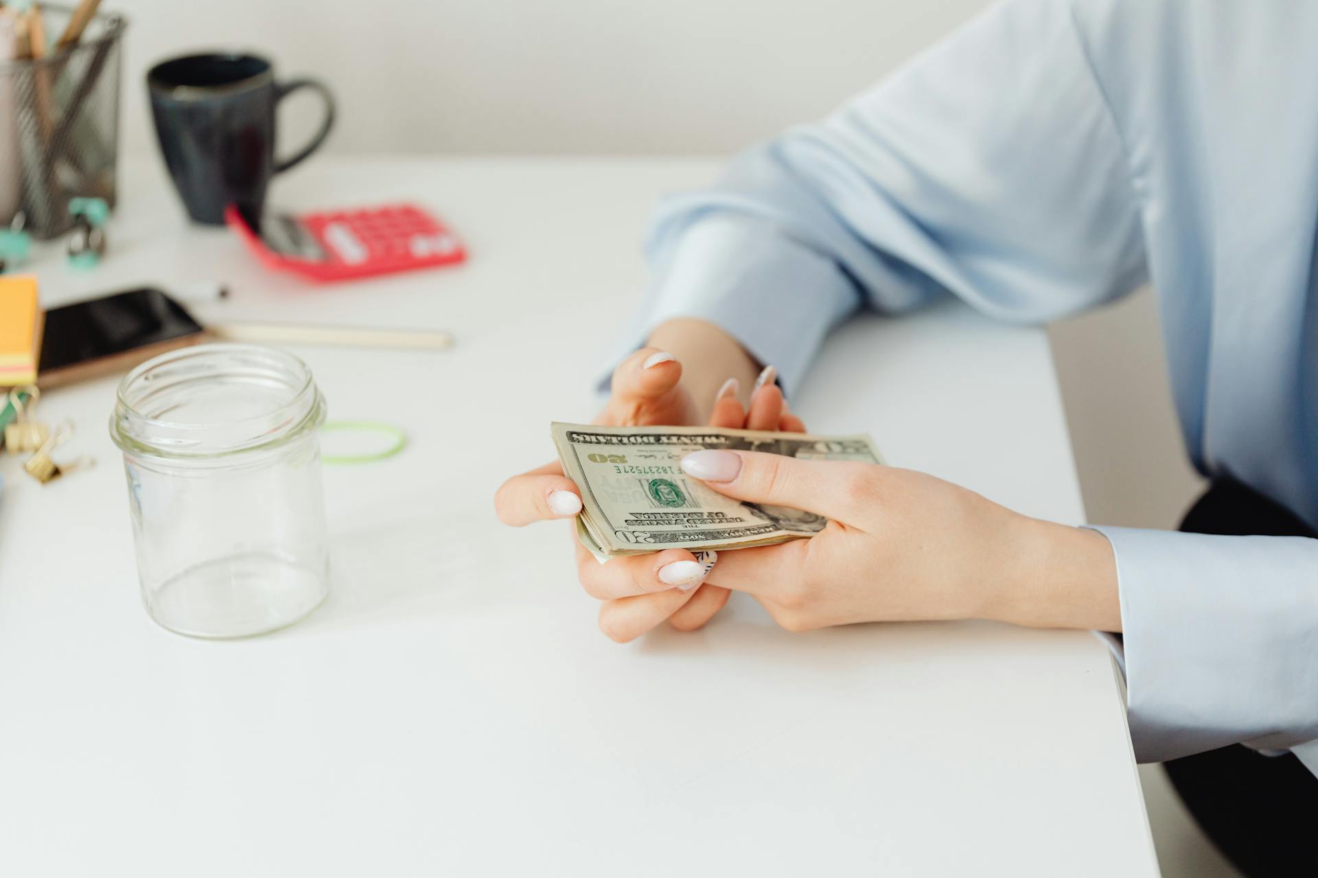 Person Sitting by the Table Holding Dollar Bills