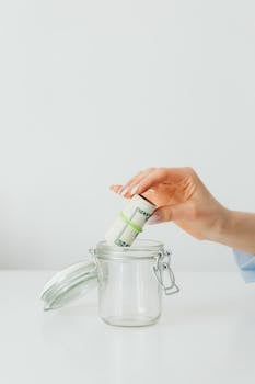 A woman placing a rolled stack of banknotes in a glass jar, ideal for finance and savings themes.