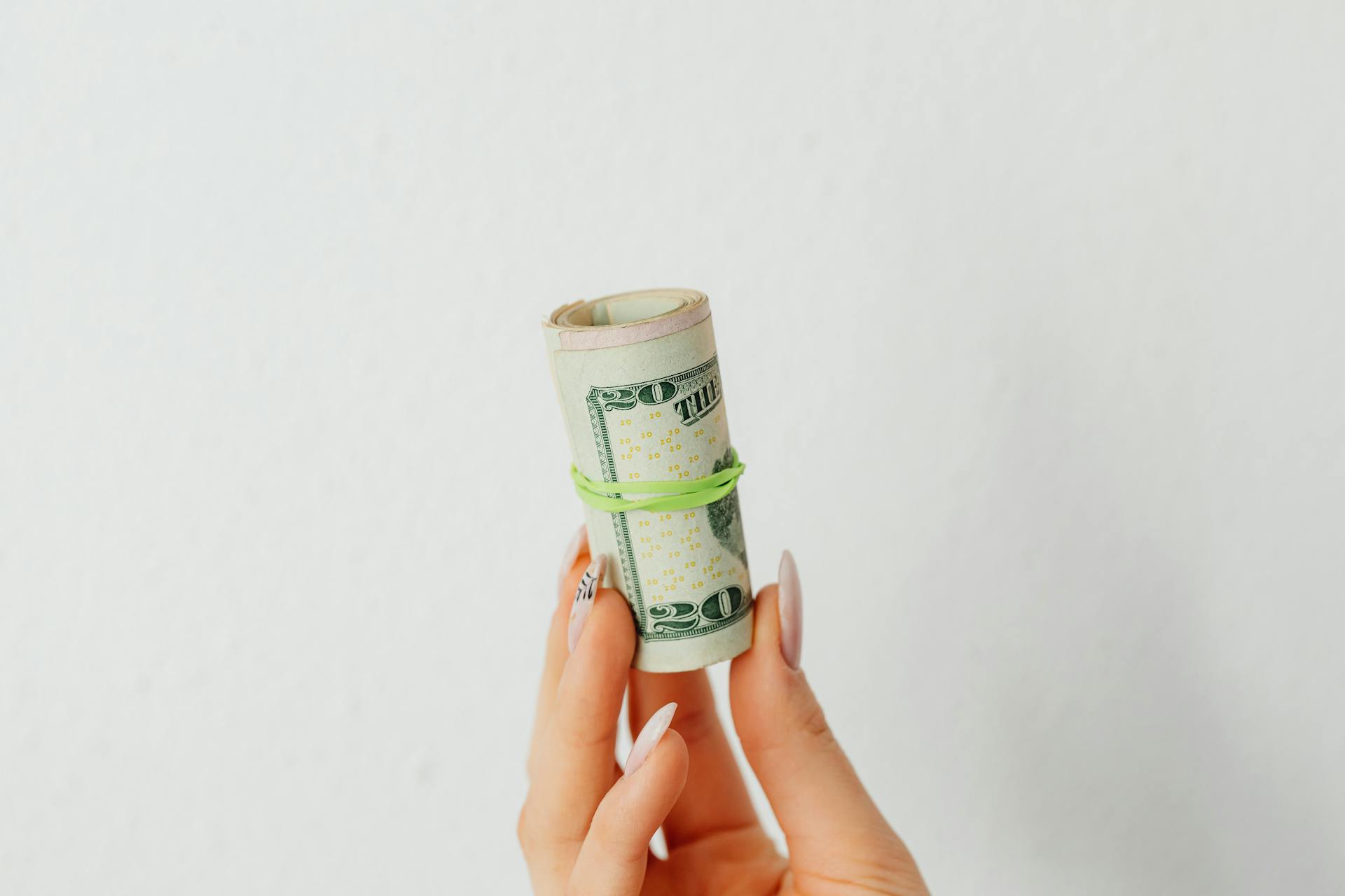 A Person Holding Rolled Paper Money on White Background