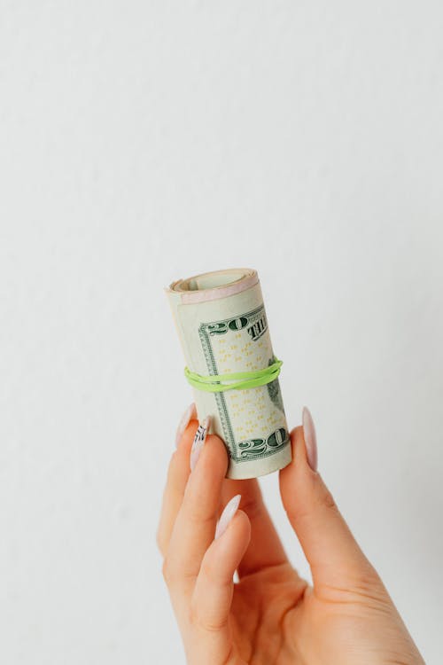 Free A Person Holding Rolled Paper Money on White Background Stock Photo