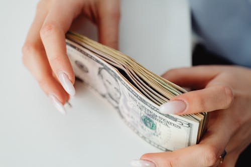 Free Close-Up Shot of a Person Holding Paper Money on White Surface Stock Photo