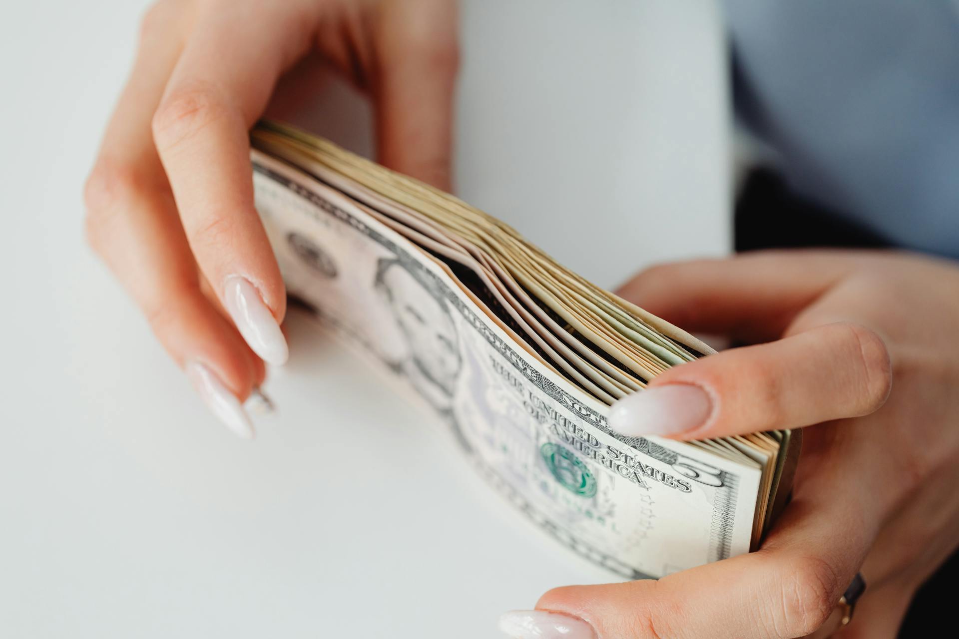 Hands carefully holding a stack of US dollar bills, representing finance and currency.