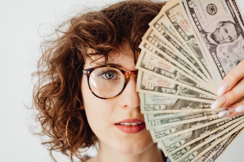 Woman in Eyeglasses Covering Her Face with Paper Money