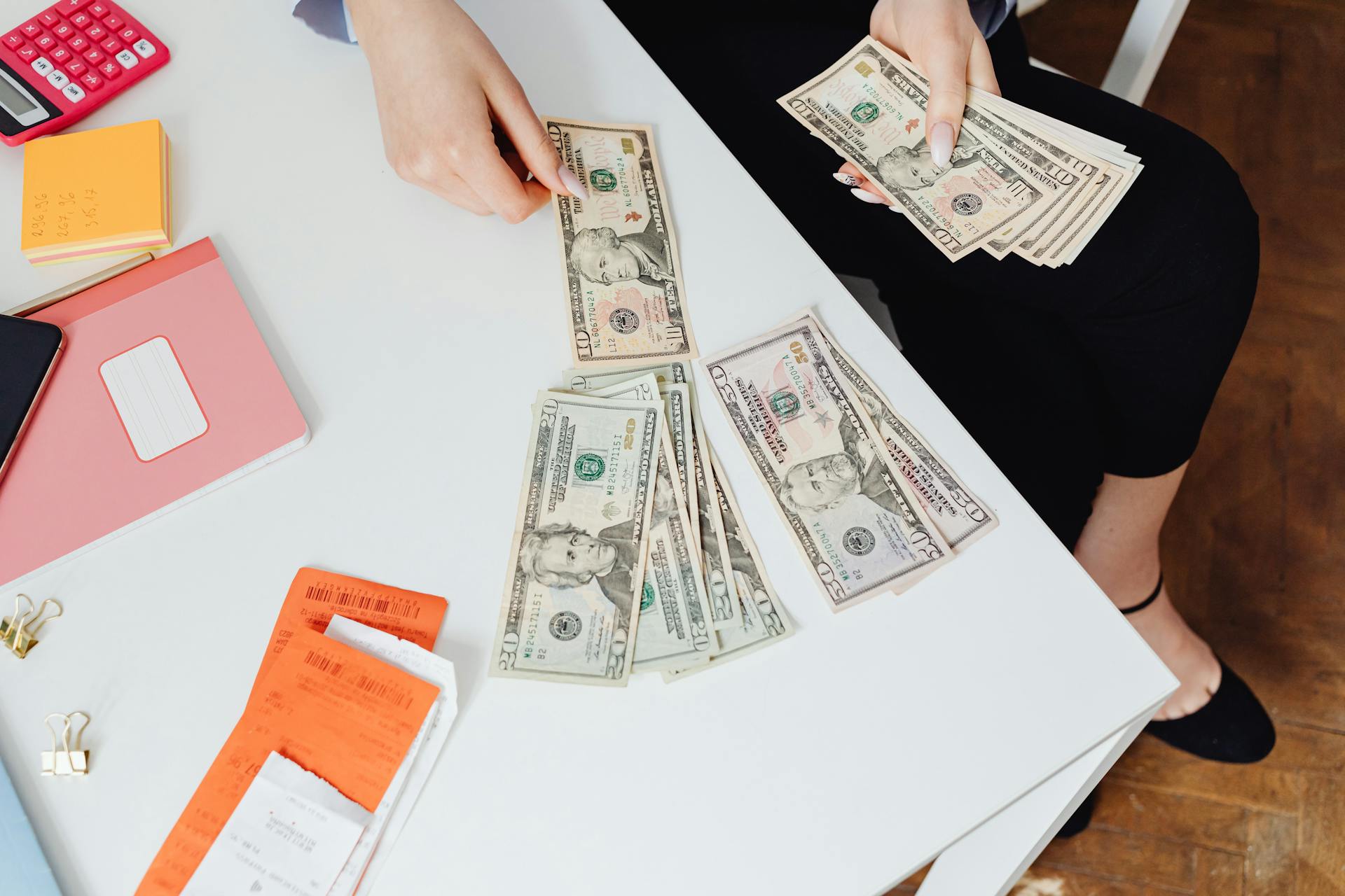 High-Angle Shot of a Person Counting Paper Money on White Table