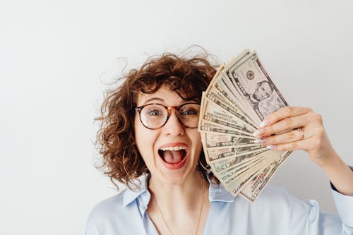 Free Happy Woman in Blue Long Sleeve Blouse Holding Money Stock Photo