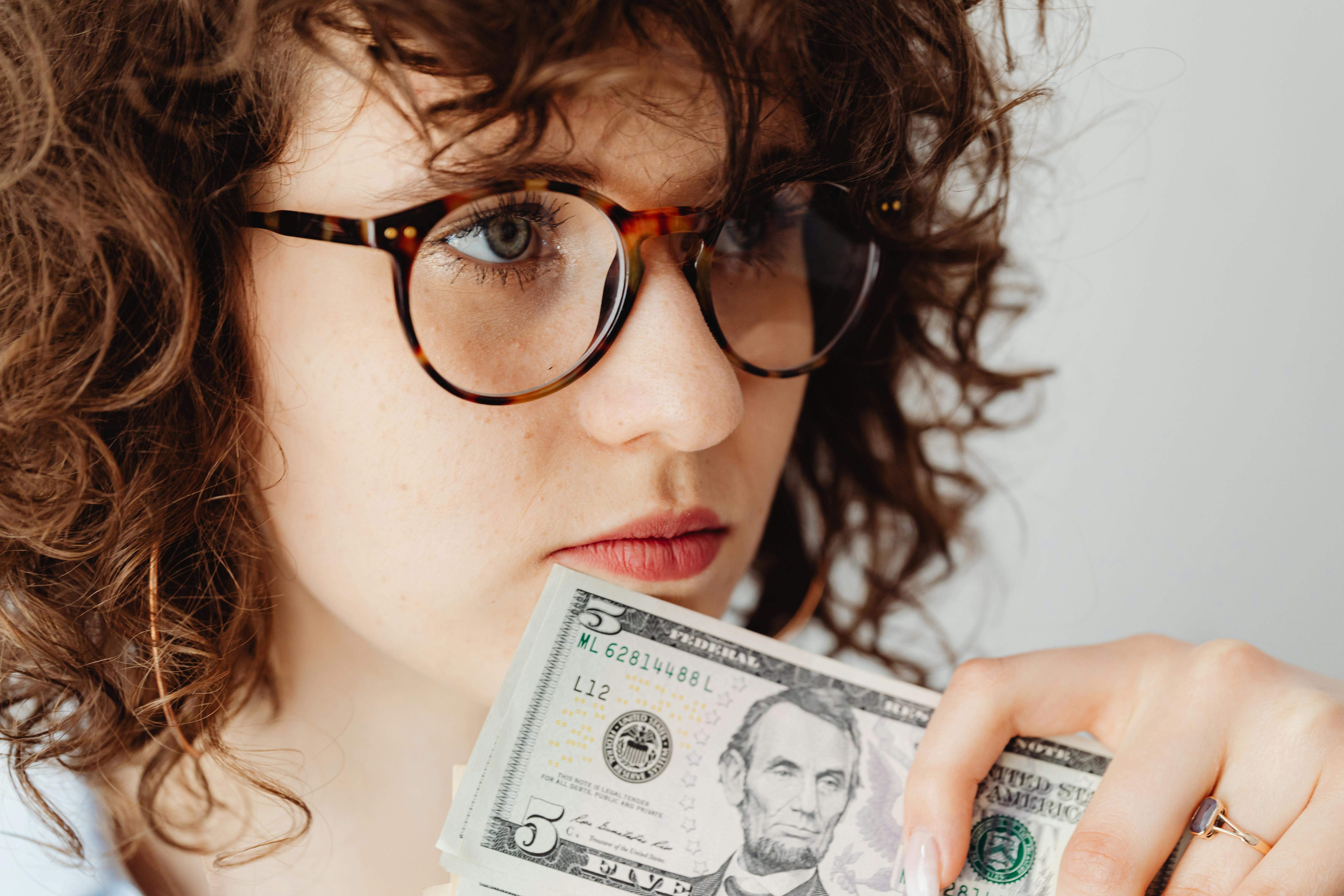 woman wearing eyeglasses holding money