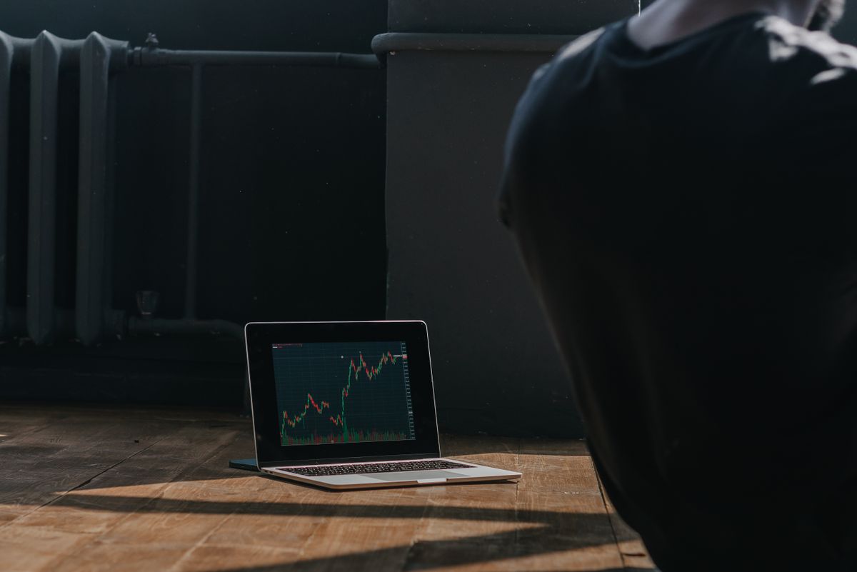 A person observing cryptocurrency price trends on a laptop screen indoors