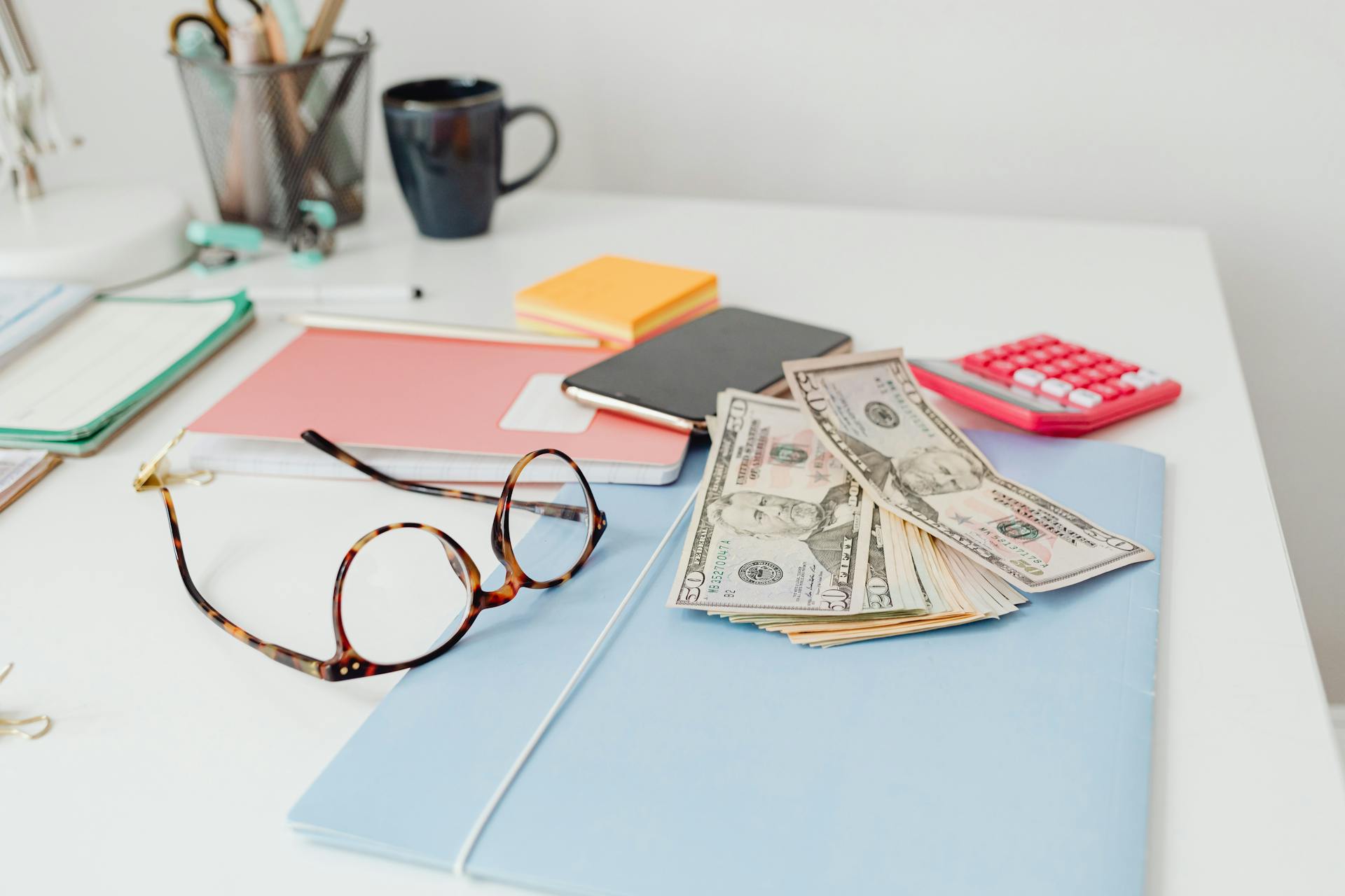 Office desk setup with eyeglasses, dollar bills, and stationary items. Perfect for finance or business themes.