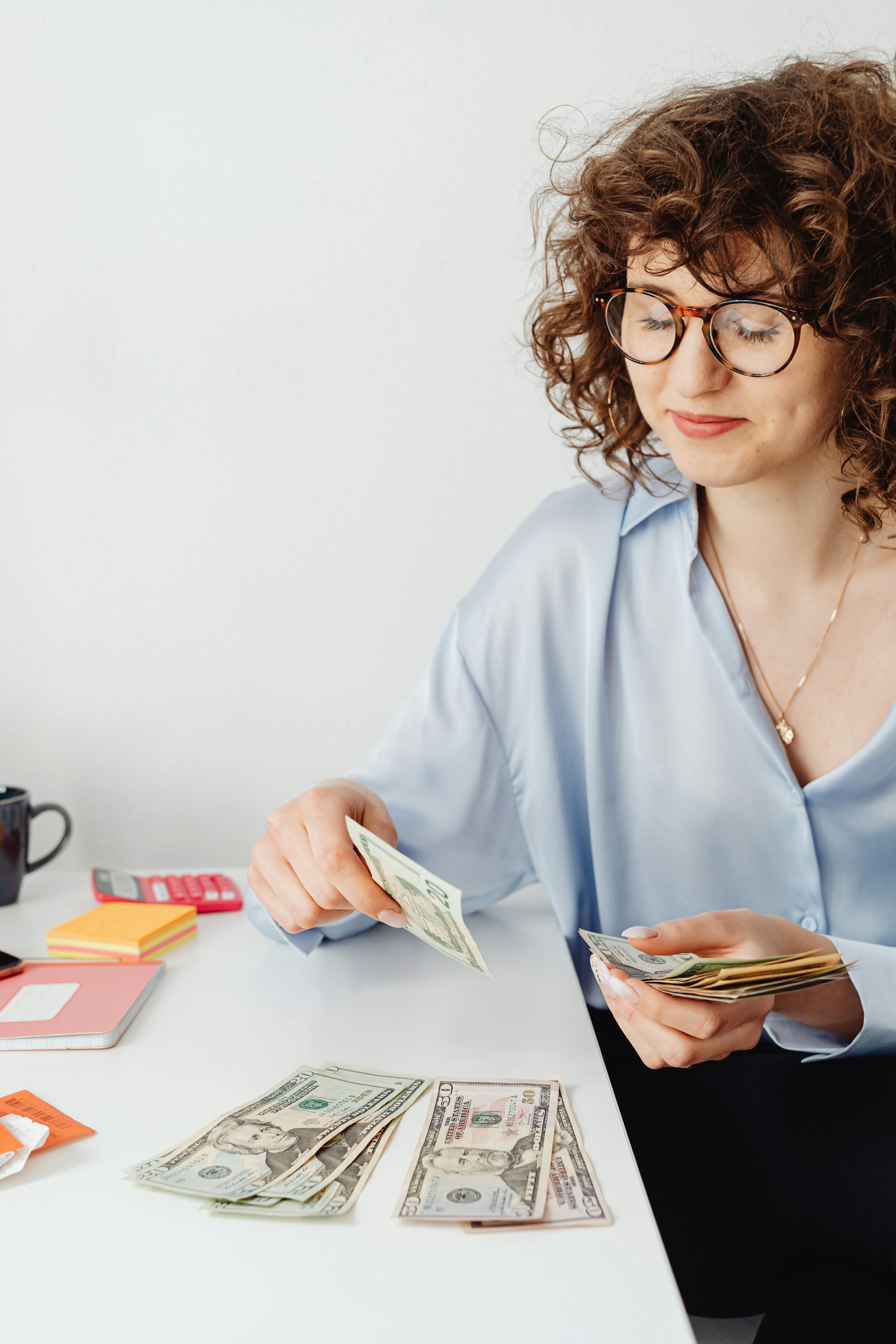 woman counting money on white table