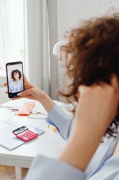 Young woman taking a selfie with smartphone in a bright room using a smartphone.