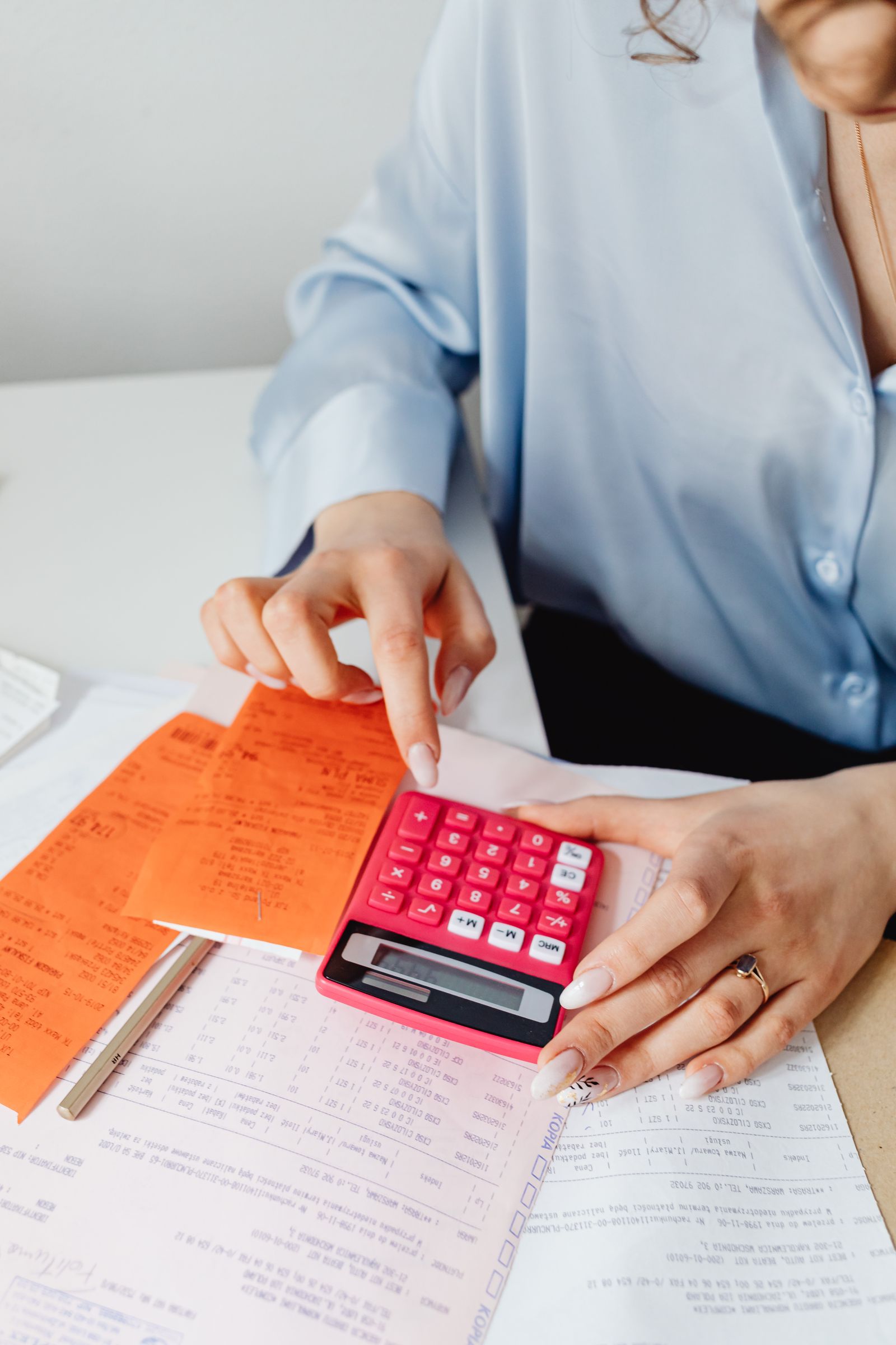 Free Person calculating finances with pink calculator and receipts, close-up view. Stock Photo