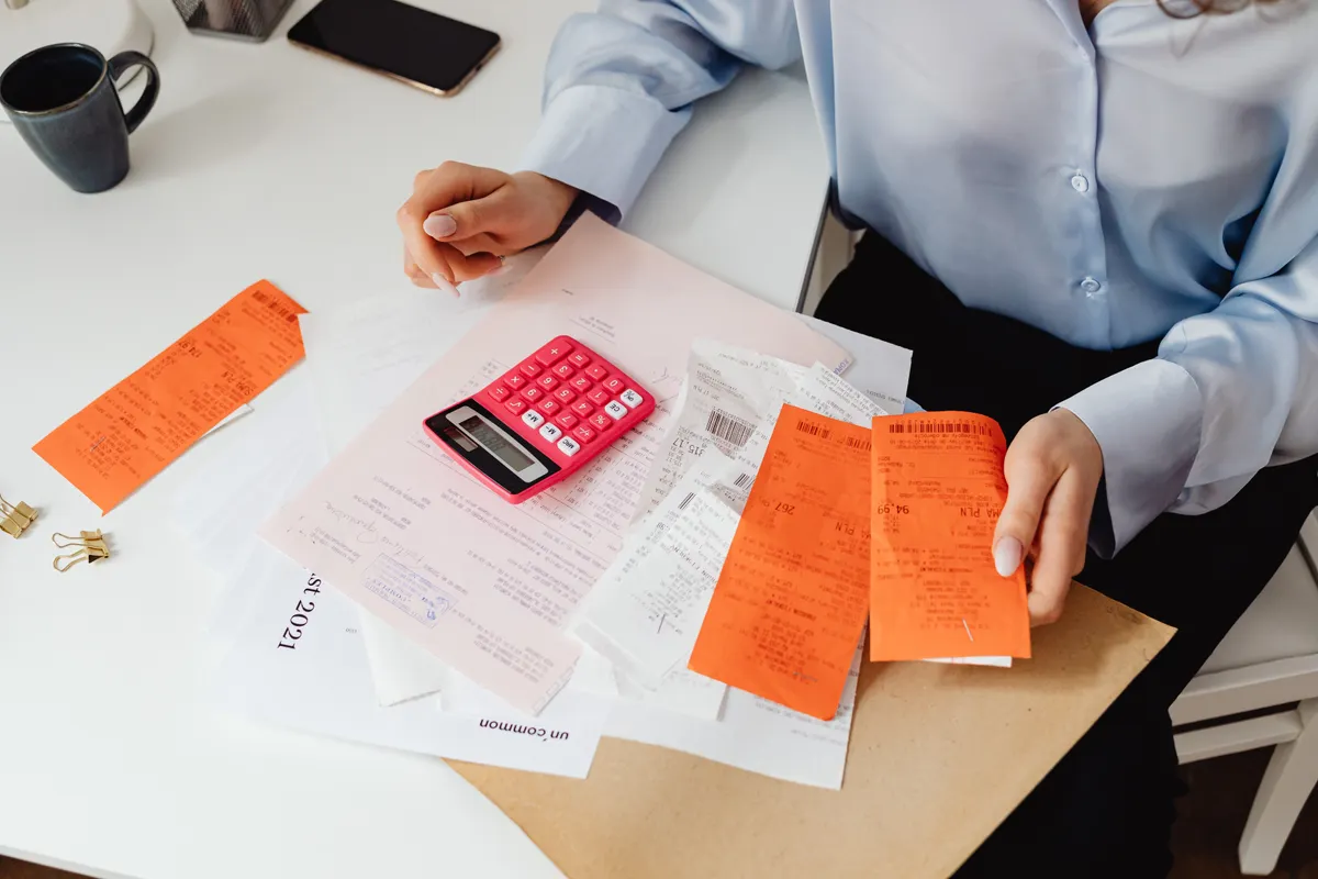 Person reviewing receipts and expense records with a calculator