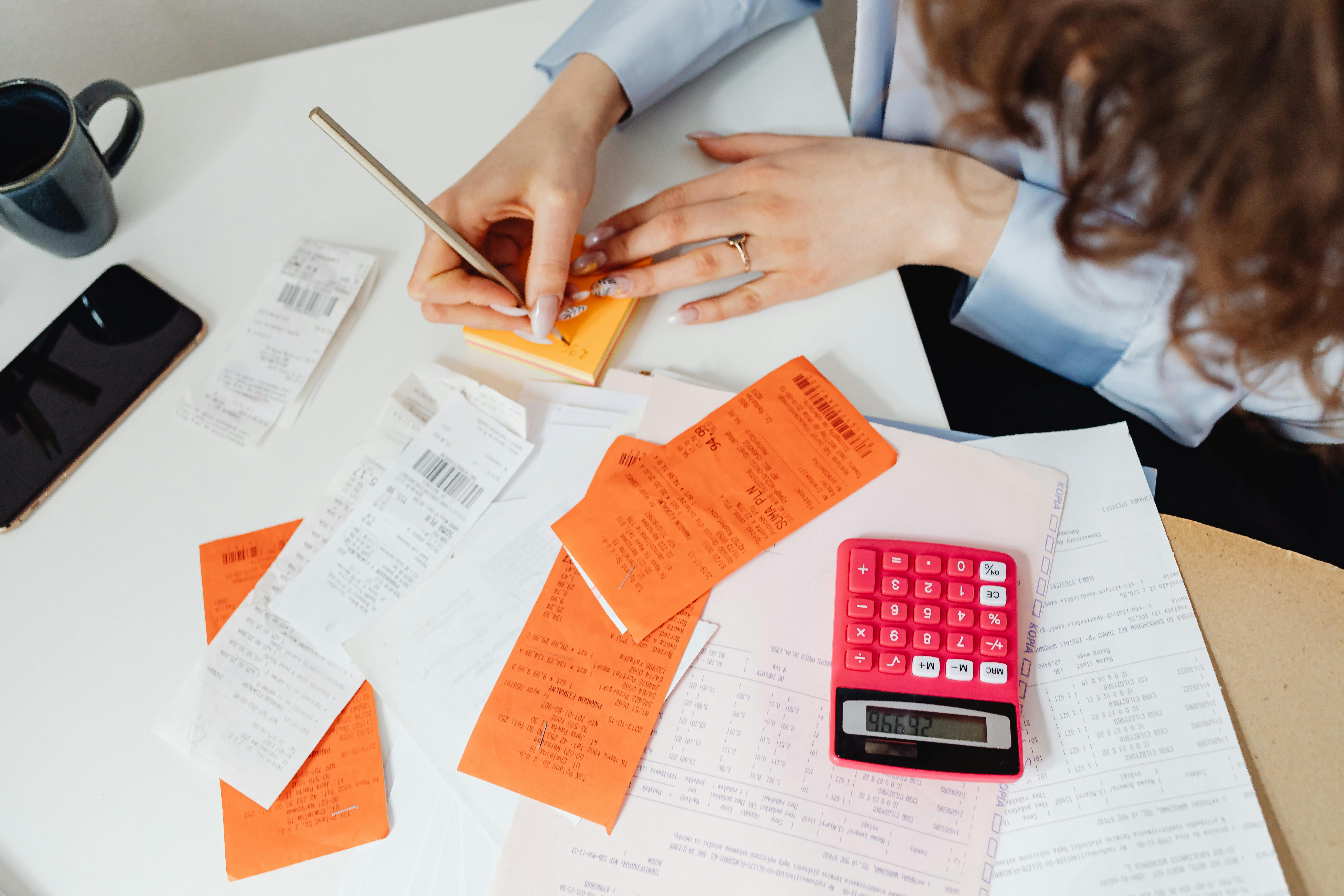 Una mujer hace un balance de sus finanzas personales con un cuaderno y una calculadora