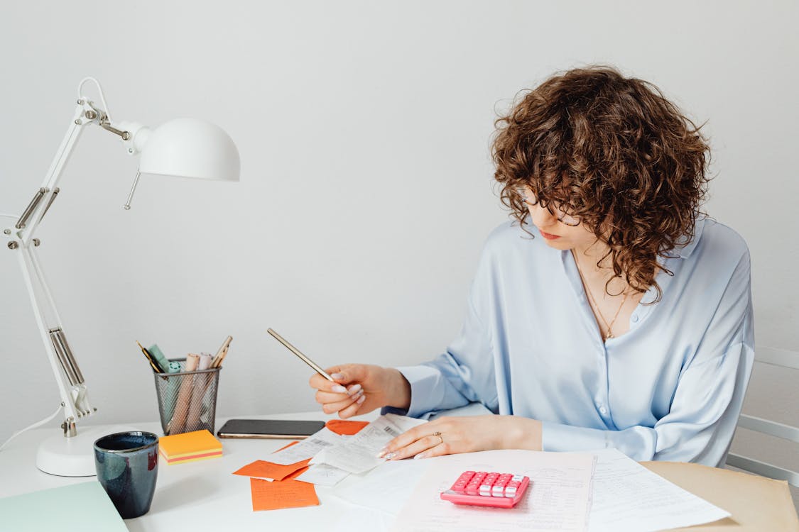 Free Woman Checking Receipts on Wooden Table Stock Photo