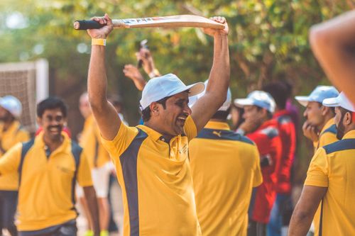 Free A cricketer in yellow uniform celebrating with a cricket bat raised in triumph outdoors. Stock Photo
