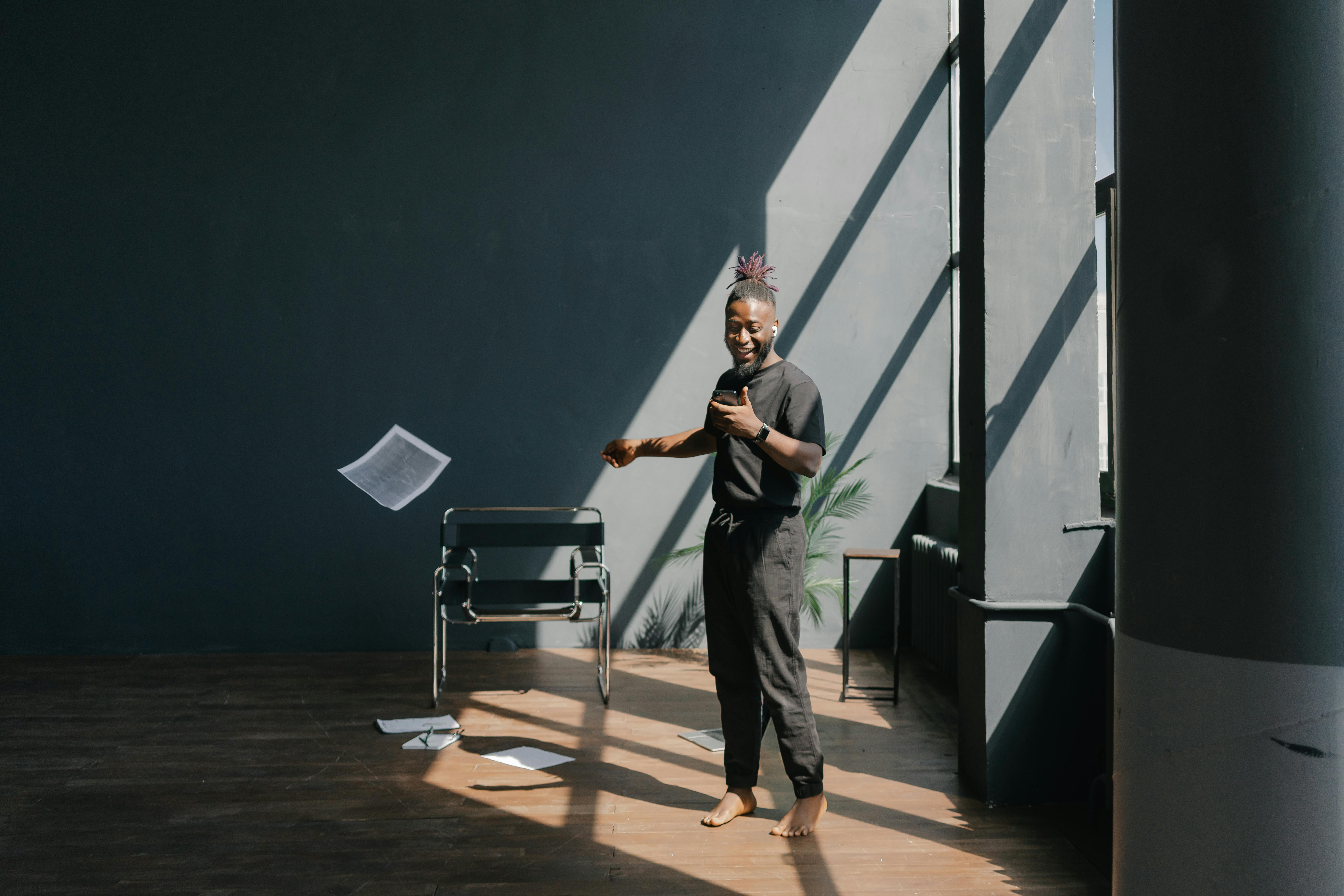 Free Man in Black T-shirt and Black Pants Standing on Brown Wooden Floor Stock Photo