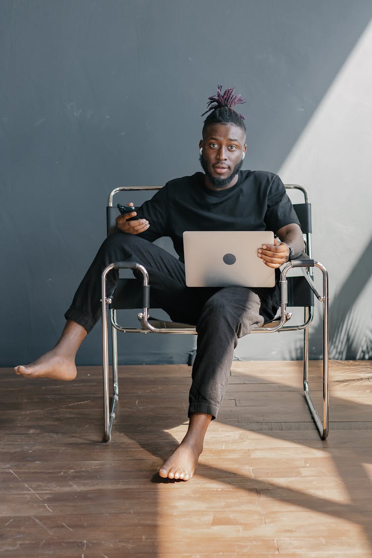 Man In Black Shirt Sitting On Black Chair Using Laptop