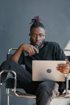 Focused young black man using a laptop and smartphone indoors. Modern and relaxed.