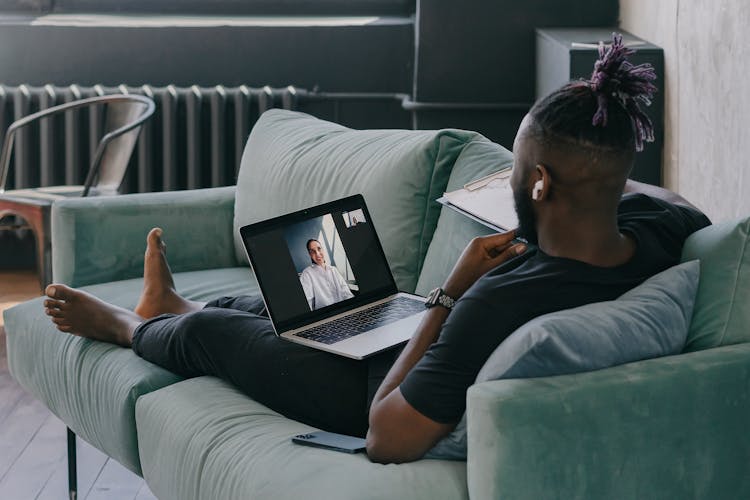 Man Using A Laptop While Lying On The Couch