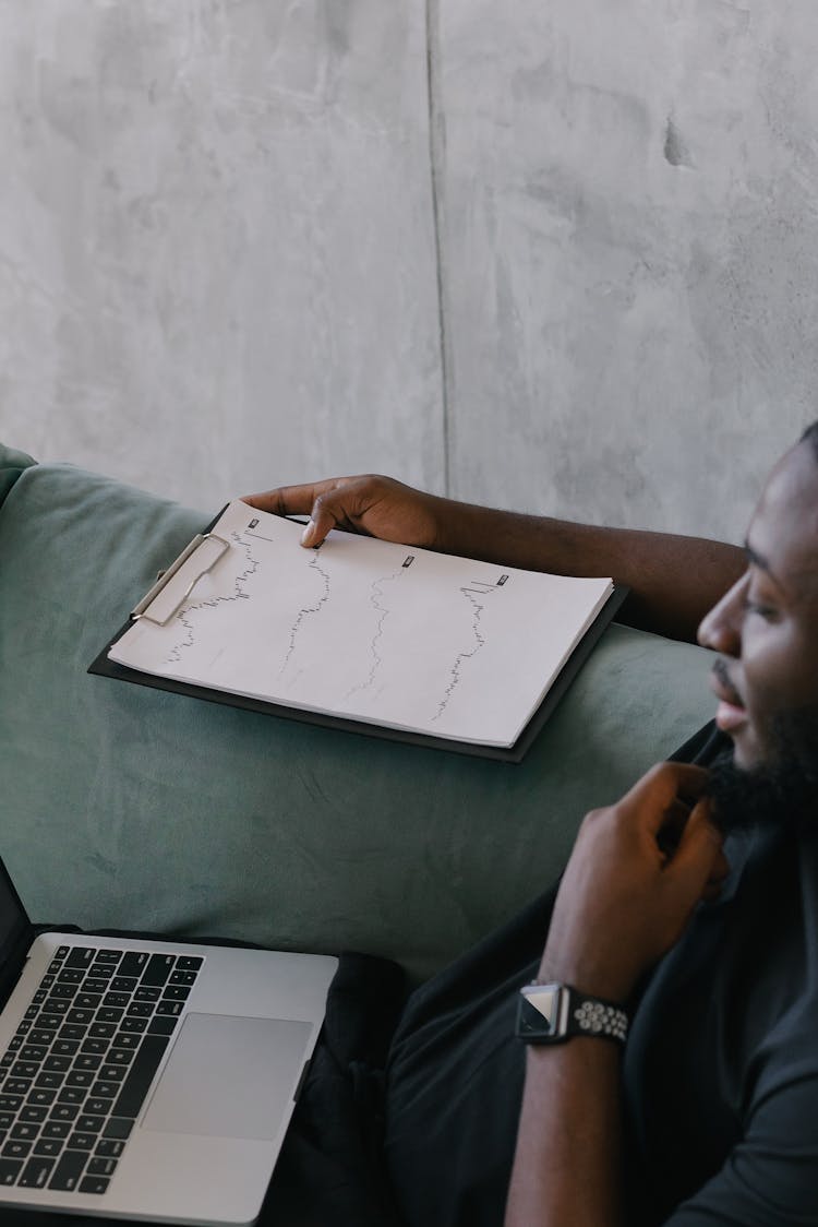 Man Sitting On Couch Holding A Clipboard 