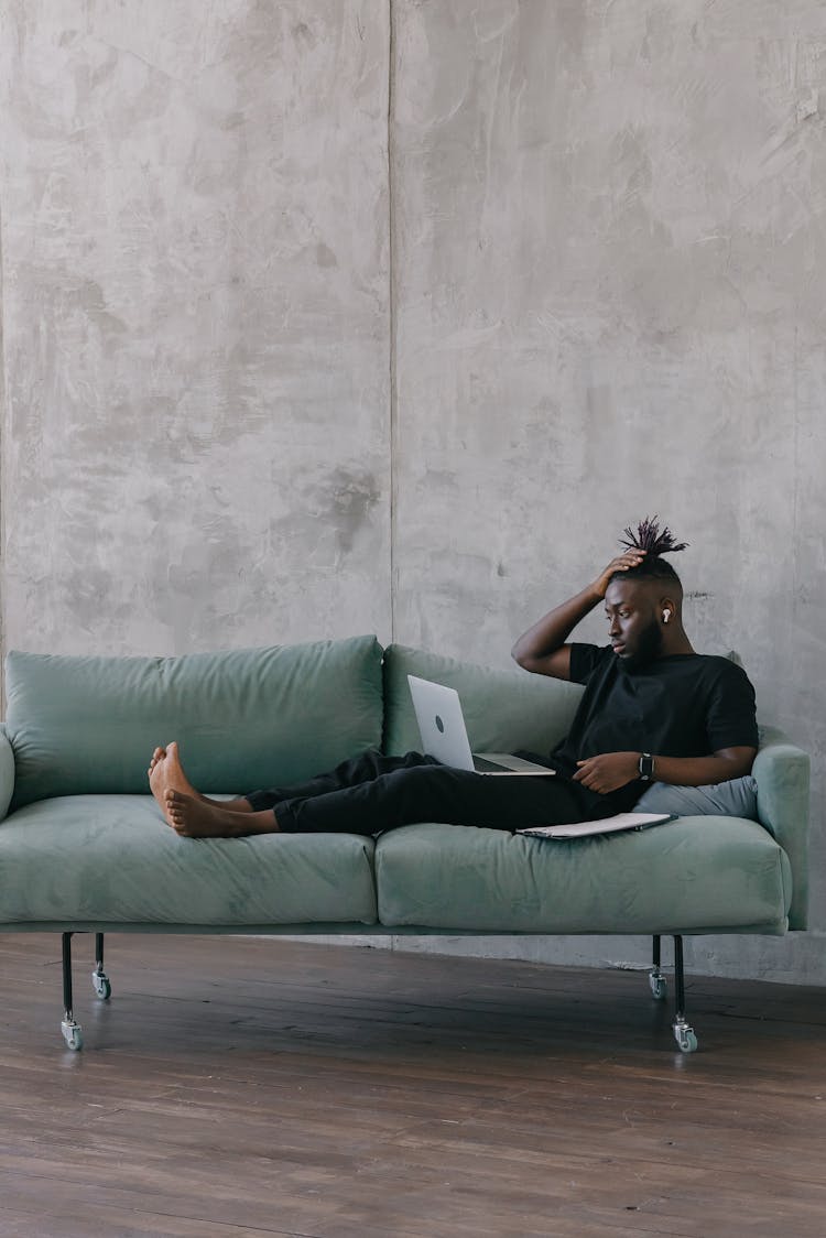 Man Sitting On The Couch While Using His Laptop