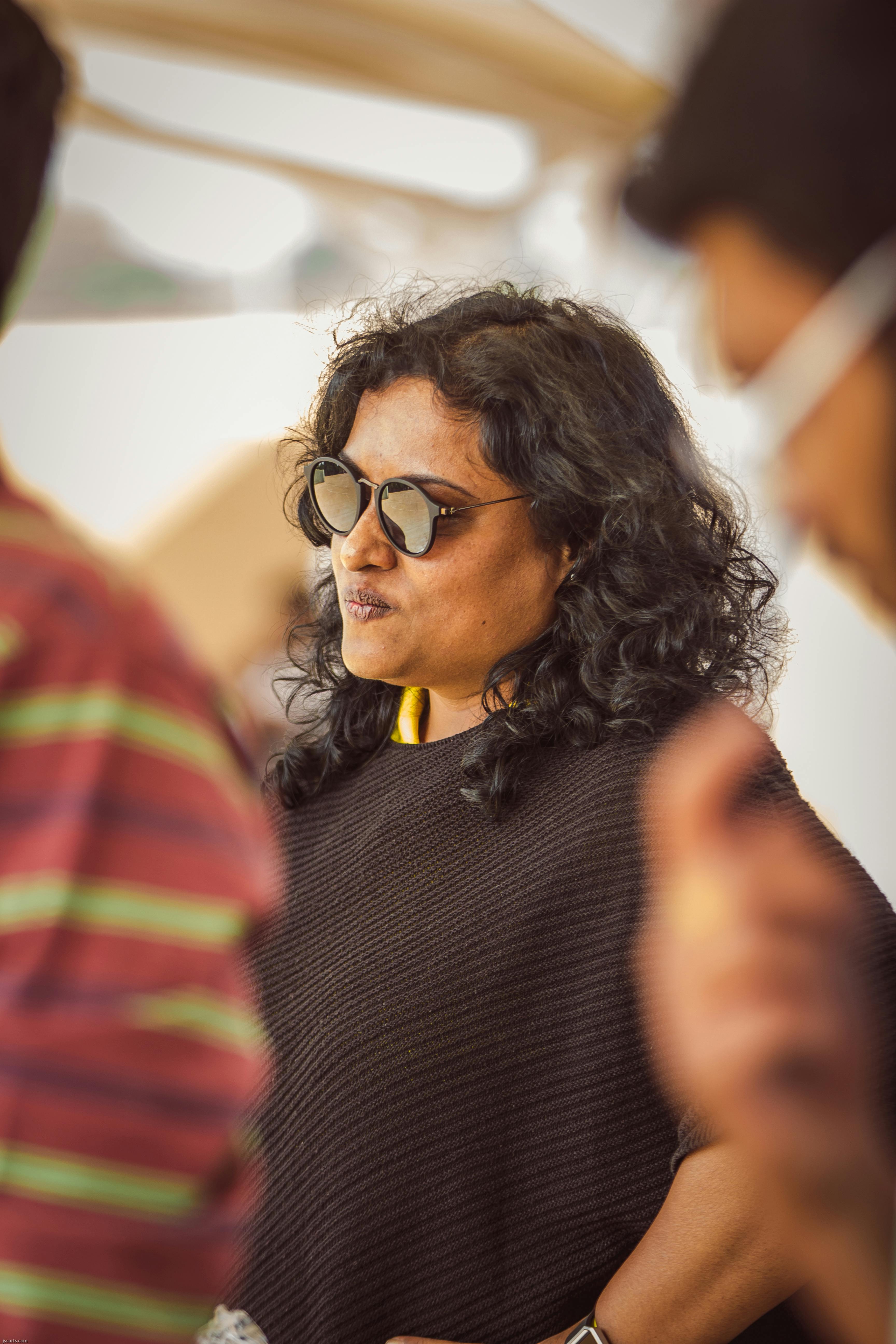 Stylish woman with curly hair wearing sunglasses in a casual setting.