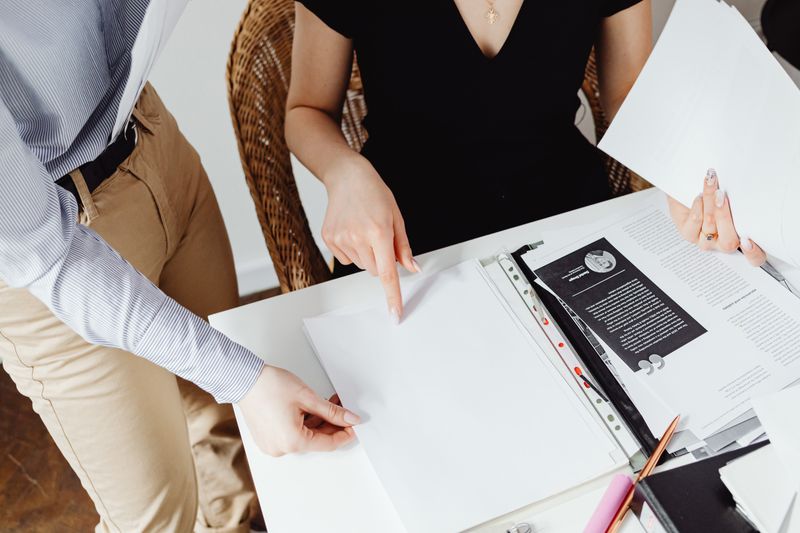 Two colleagues reviewing paperwork together, pointing out detail on a document