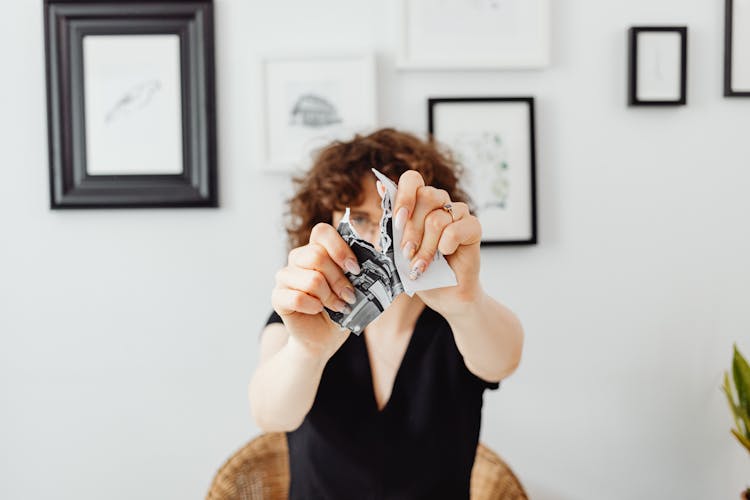 A Person Tearing A Piece Of Paper Into Pieces