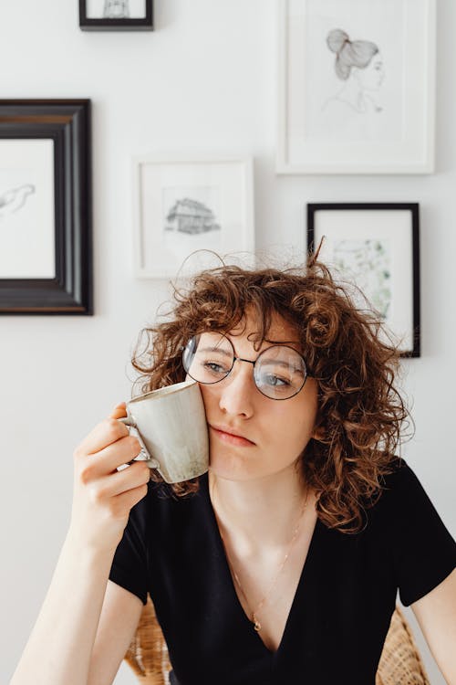 Free Woman in Black V-Neck Shirt Looking Unhappy while Holding a Mug Stock Photo