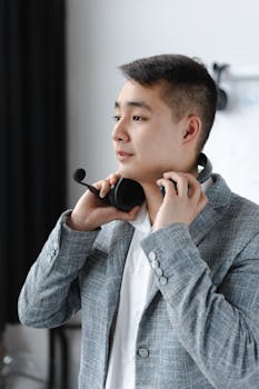 Asian man in a gray suit putting on a headset, symbolizing modern customer support.
