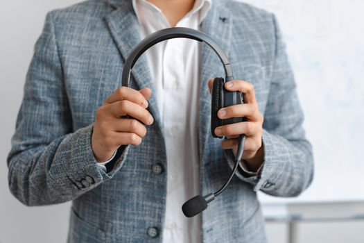 Close-up of a business professional in a blazer holding headphones, signaling communication or tech support.