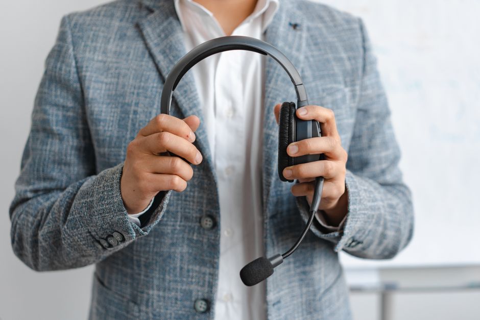 Close-up of a business professional in a blazer holding headphones, signaling communication or tech support.