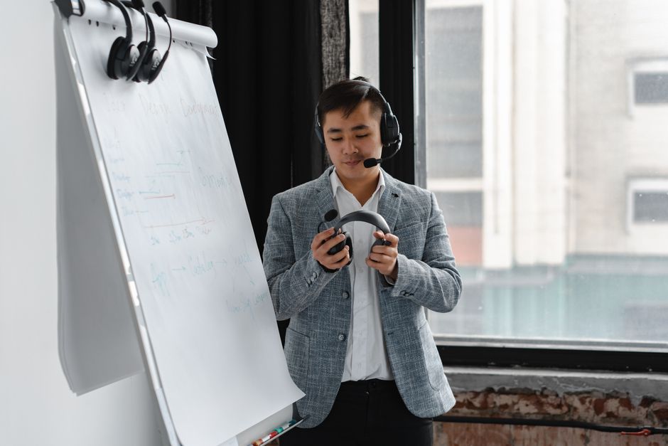 Asian call center agent holding headset in an office setting