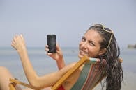 一位微笑的女人在马耳他姆加尔海滩拿着智能手机享受假期