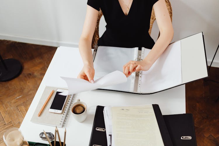 A Person Folding A White Piece Of Paper