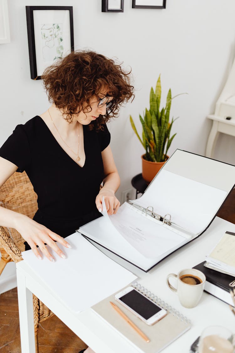 Woman Sitting At The Desk And Looking At Documents 