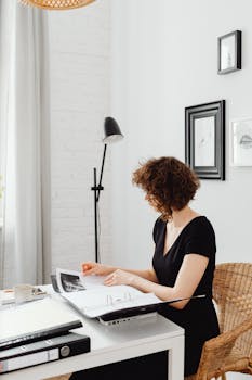 Caucasian woman organizing documents in a modern home office setting.