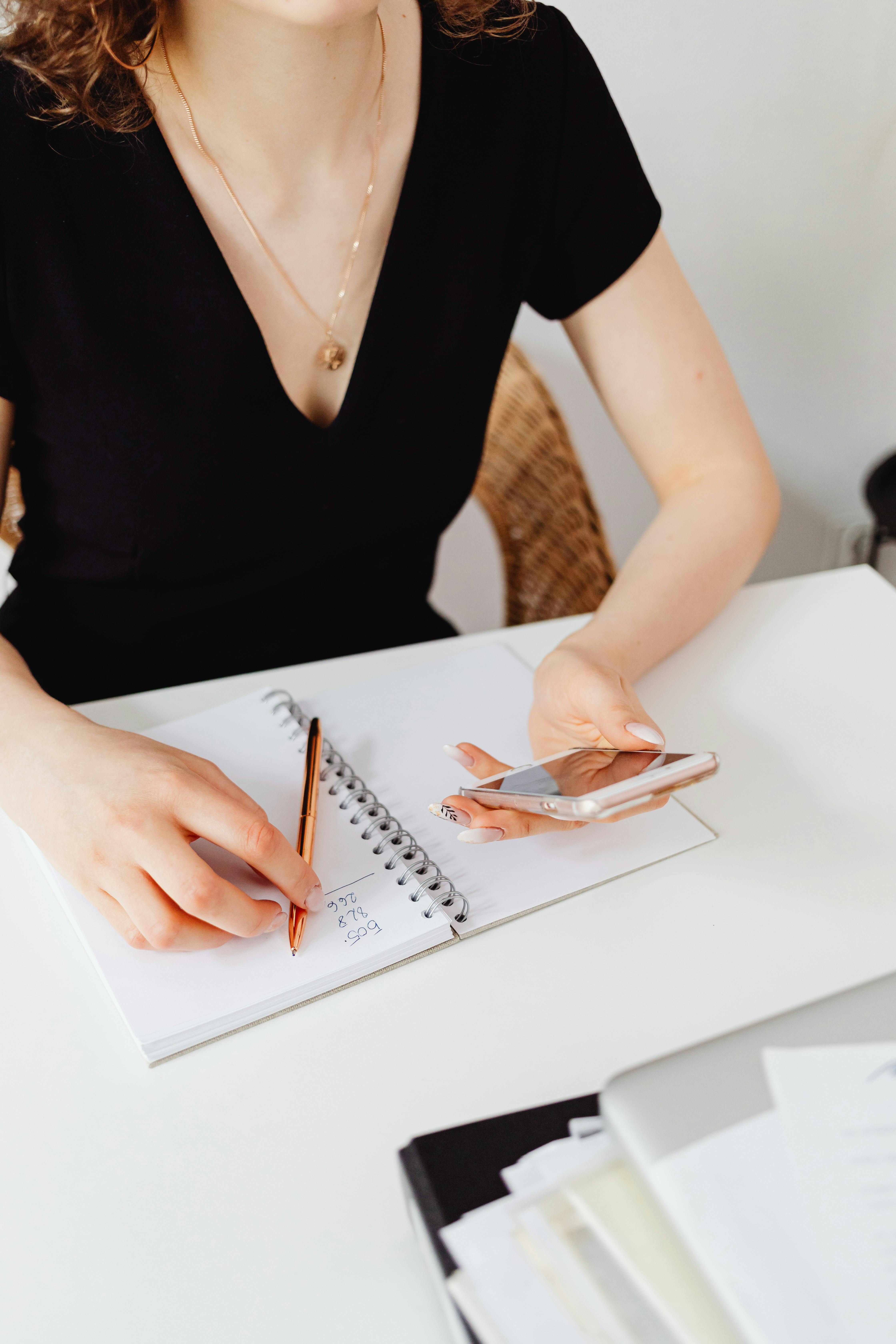 a woman holding a pen and her cell phone