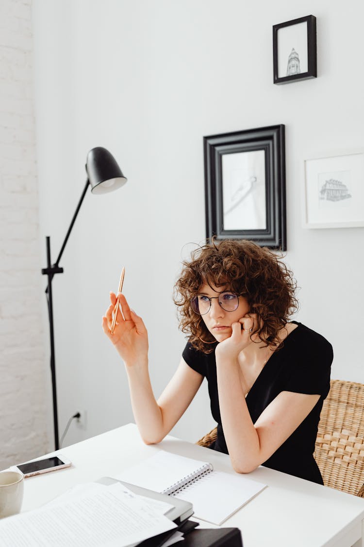 A Woman Thinking While Holding Her Pen