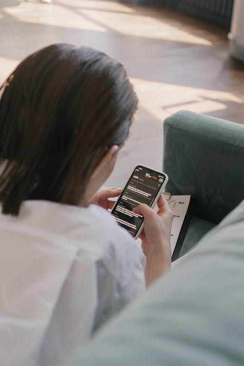 Free A Woman Using Her Smartphone on a Couch Stock Photo