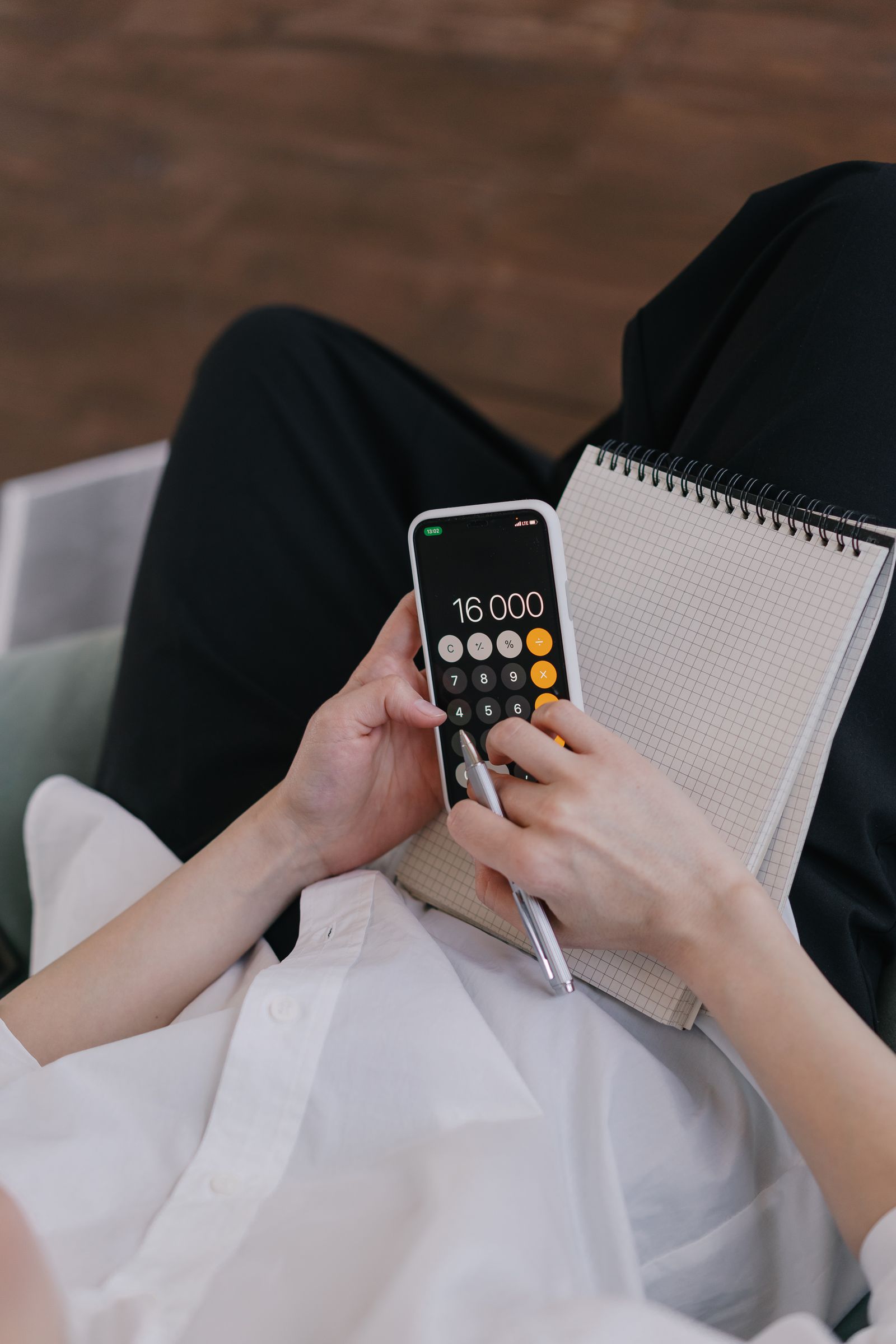 Persona calculando un presupuesto mensual desde su teléfono antes de negociar una deuda